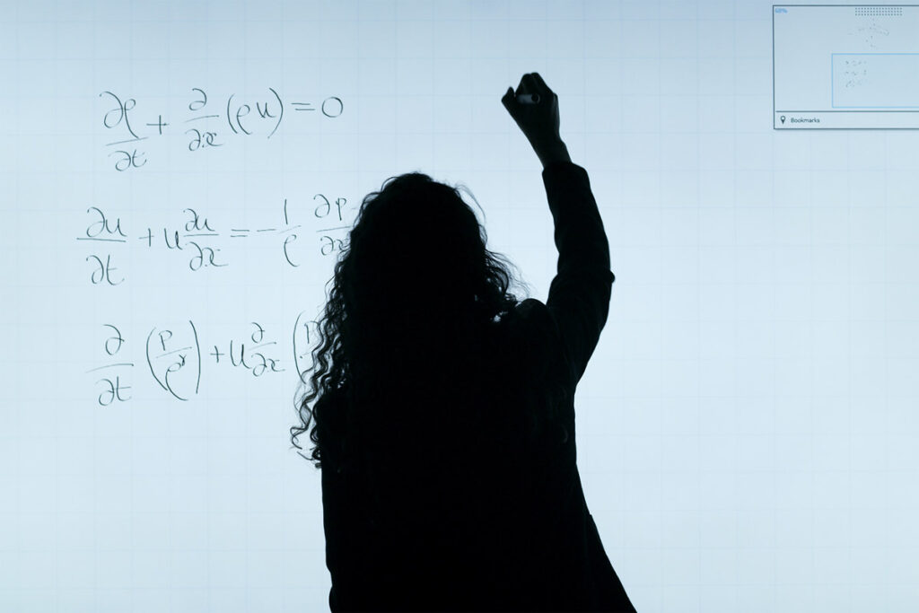 Woman drawing an equation on whiteboard